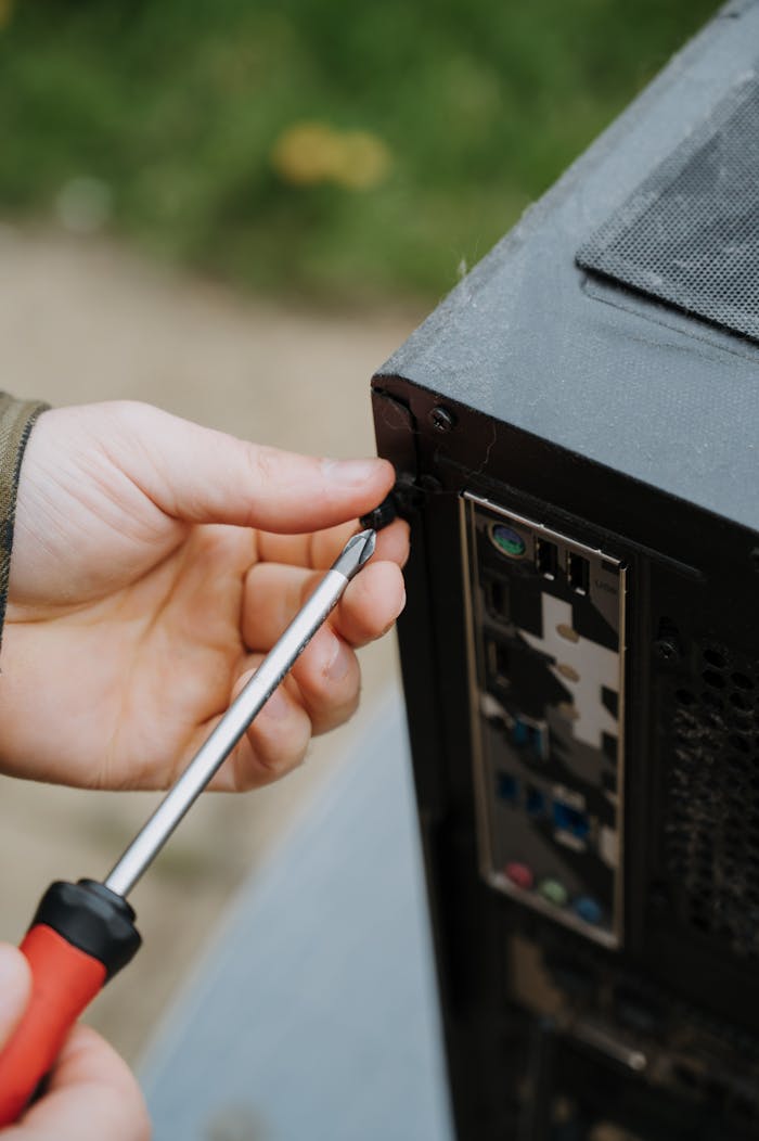 who-we-are Close-up of a person tightening screws on a PC case for maintenance.
