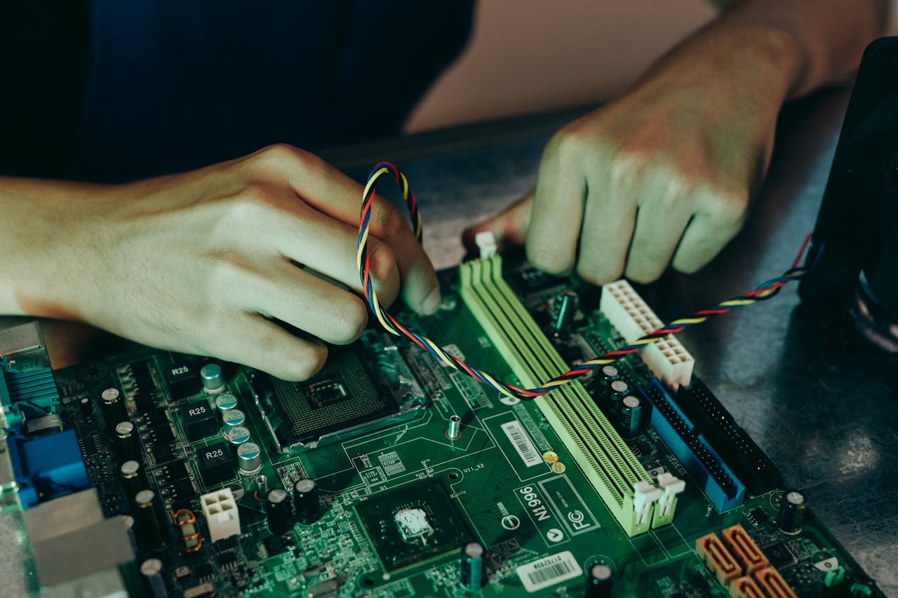 why-choose-us Person assembling computer motherboard with colorful wires, showcasing technology and engineering.